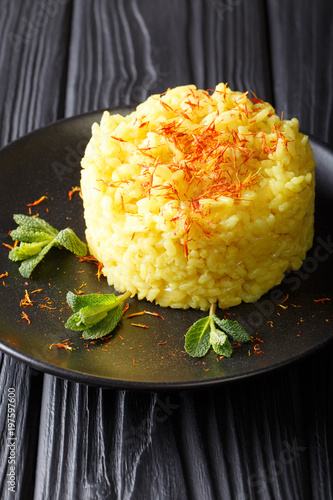 traditional risotto alla milanese with saffron is decorated with mint closeup on a plate. vertical