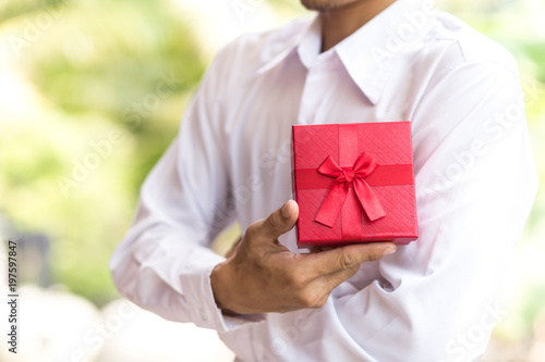 Business man hold red gift box in hands.