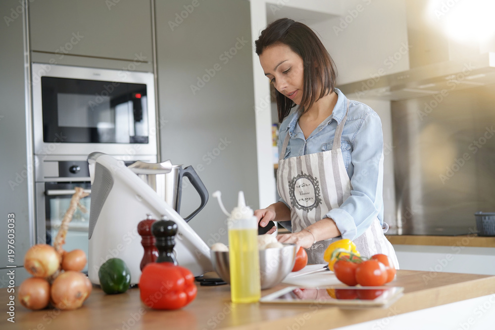 Woman using kitchen robot to prepare dinner Woman using kitchen robot to prepare dinner
