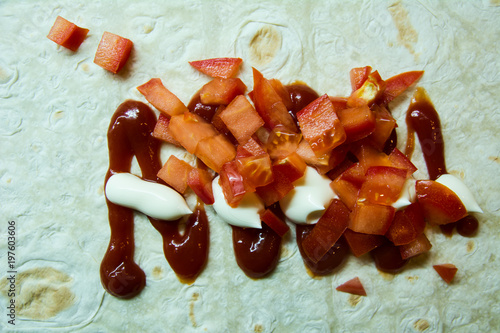 Slices of sliced tomato mayonnaise and ketchup on pita bread photo