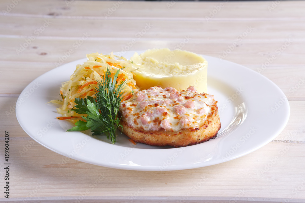 Fish cutlet with ham and melted cheese topping served with pickled cabbage and mashed potato Fish cutlet with ham and melted cheese topping served with pickled cabbage and mashed potato