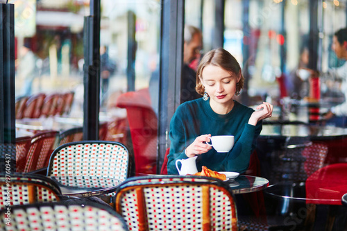 Young elegant woman drinking coffee in cafe in Paris, France