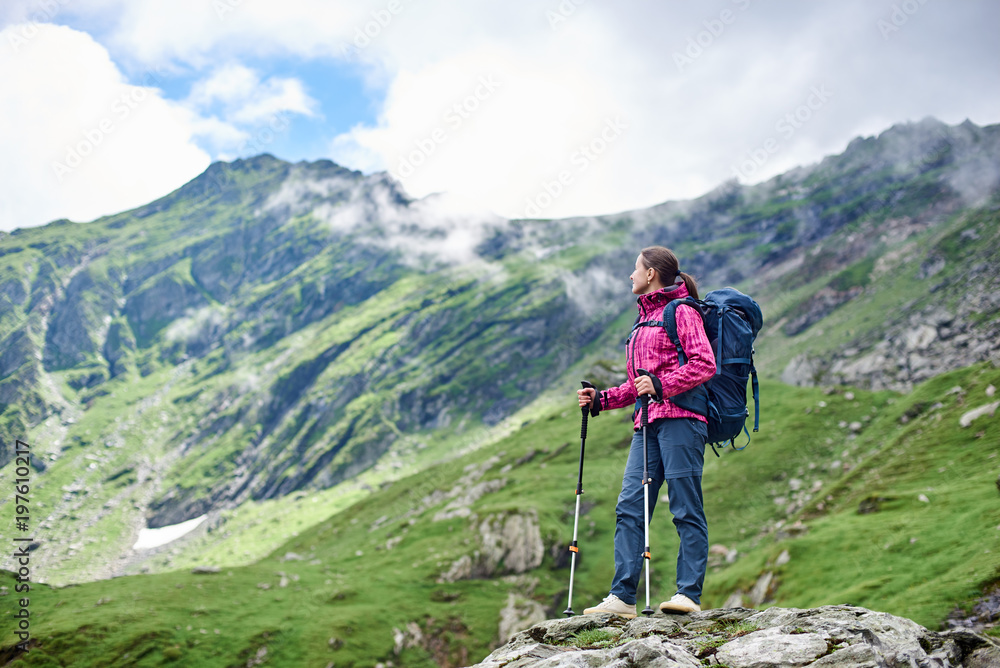 Woman backpacker resting while hiking standing on top of a rock enjoying fantastic mountain scenery around copyspace relax rest camping hiker hobby lifestyle enjoyment nature.
