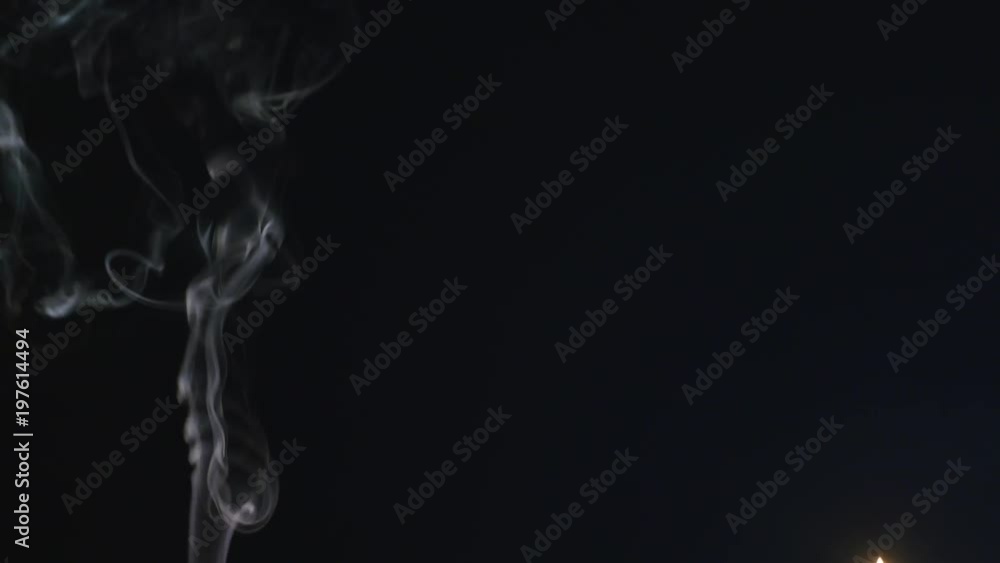 Close up of burning incense sticks with smoke over black background Close up of burning incense sticks with smoke over black background