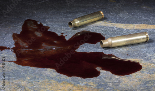 Foto Pair of empty AR-15 shells with blood on a rock