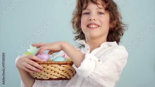 A child holds a Easter bunny and a set of decorative Easter eggs. The boy laughs cheerfully. Slow Motion photo