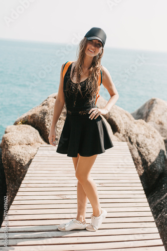 smiling girl posing on wooden pier at rocks and sea
