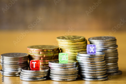 TAX Concept with alphabet block on a gold stacked of coins.