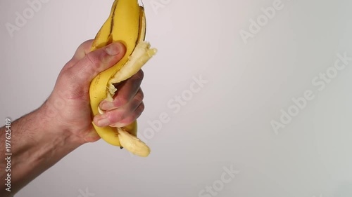 Vitamin and healthy eating. Ripe mellow banana fruit squeezed, mashed, or crushed with yellow skin and flesh drops, splashes, on white background photo
