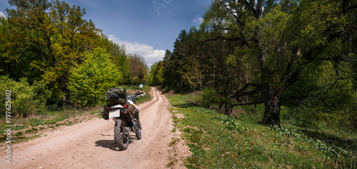 Adventure motorcycle on dirt forest road, enduro, active lifestyle, travel lover concept