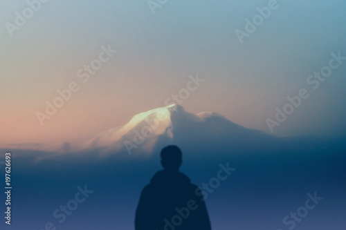 man silhouette hiker stands outdoors watching of highest mountain at sunset. concept nature and human race. copy space