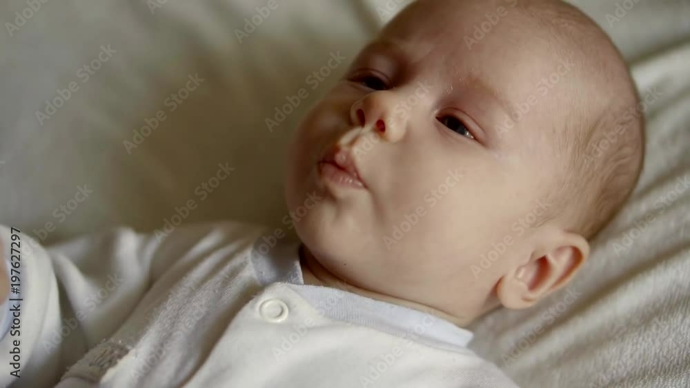 A cute little child looks at the camera and enjoys the white bed. A cute little child looks at the camera and enjoys the white bed.