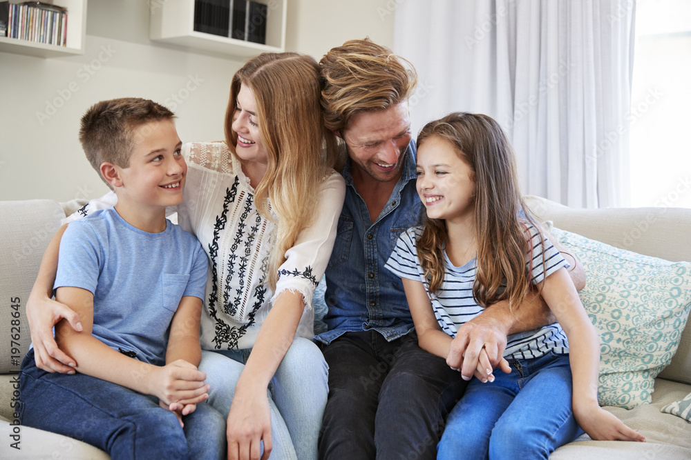 Smiling Family Relaxing On Sofa At Home Together Smiling Family Relaxing On Sofa At Home Together