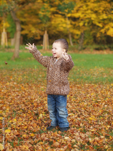 little boy playing in the park in autumn