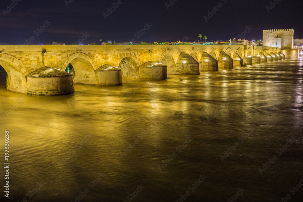 puente sobre río guadalquivir con mucha agua, larga exposición de noche
