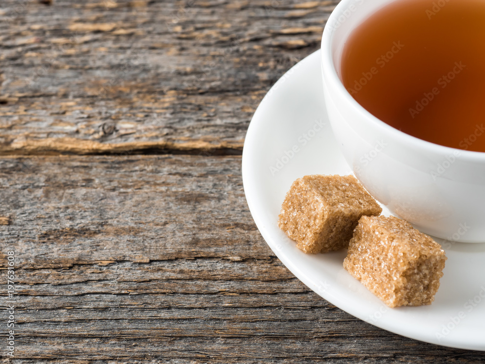 White tea Cup and saucer brown cane sugar on a rustic wooden background White tea Cup and saucer brown cane sugar on a rustic wooden background