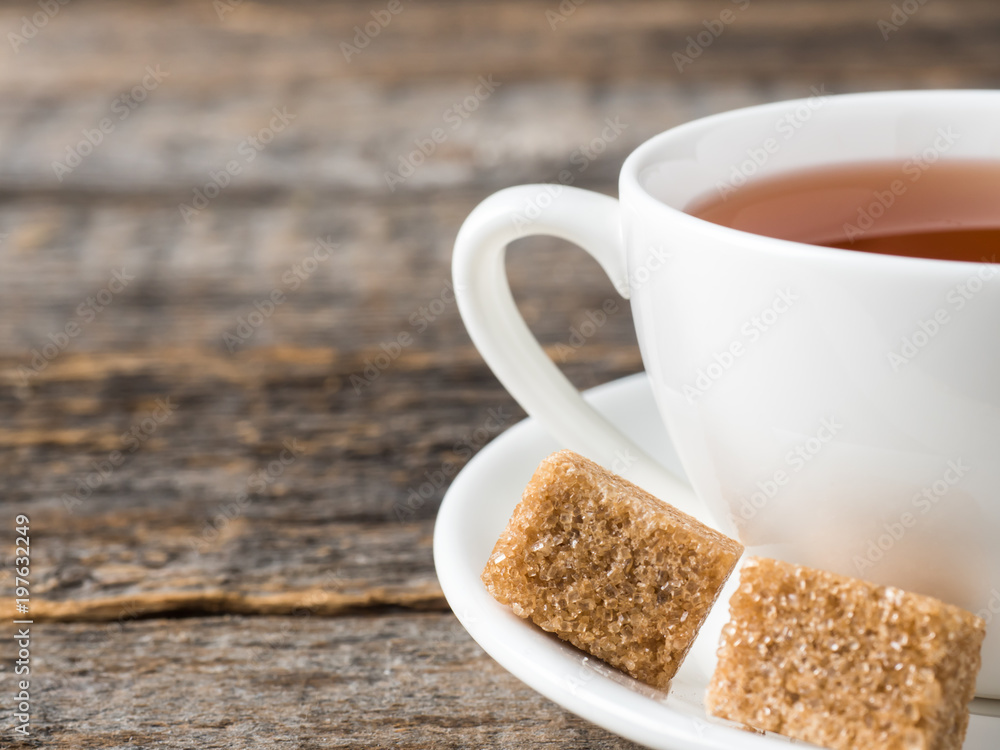 White tea Cup and saucer brown cane sugar on a rustic wooden background White tea Cup and saucer brown cane sugar on a rustic wooden background