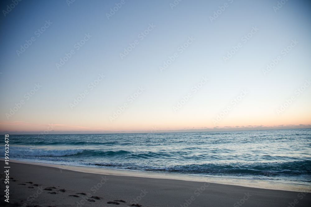 Florida Coast Beach View with Blue and Orange Sky at Sunrise or Sunset with Footprints in the Sand