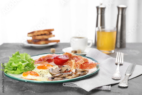 Plate with fried eggs, bacon and sauce on grey background