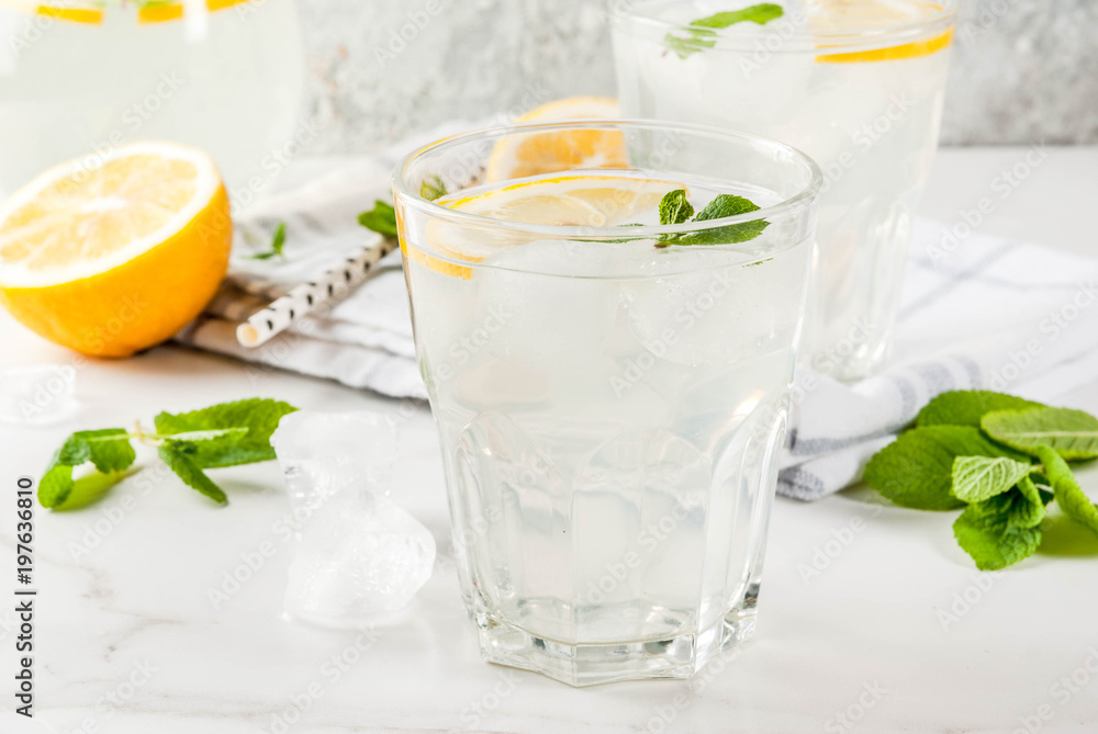 Summer refreshing drinks, mojito or lemonade with fresh mint, slices of lemon, ice, on a light background. copy space Summer refreshing drinks, mojito or lemonade with fresh mint, slices of lemon, ice, on a light background. copy space