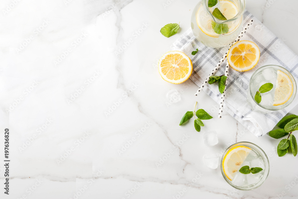 Summer refreshing drinks, mojito or lemonade with fresh mint, slices of lemon, ice, on a light background. copy space top view Summer refreshing drinks, mojito or lemonade with fresh mint, slices of lemon, ice, on a light background. copy space top view