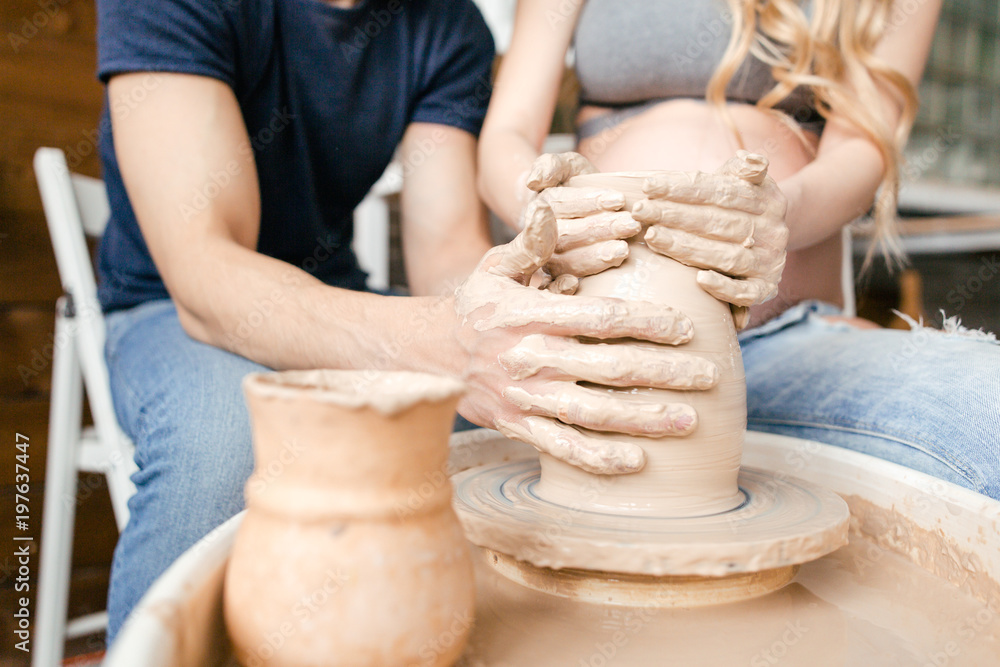 Close-up of the couple's hand makes a clay vase on a Potter's wheel