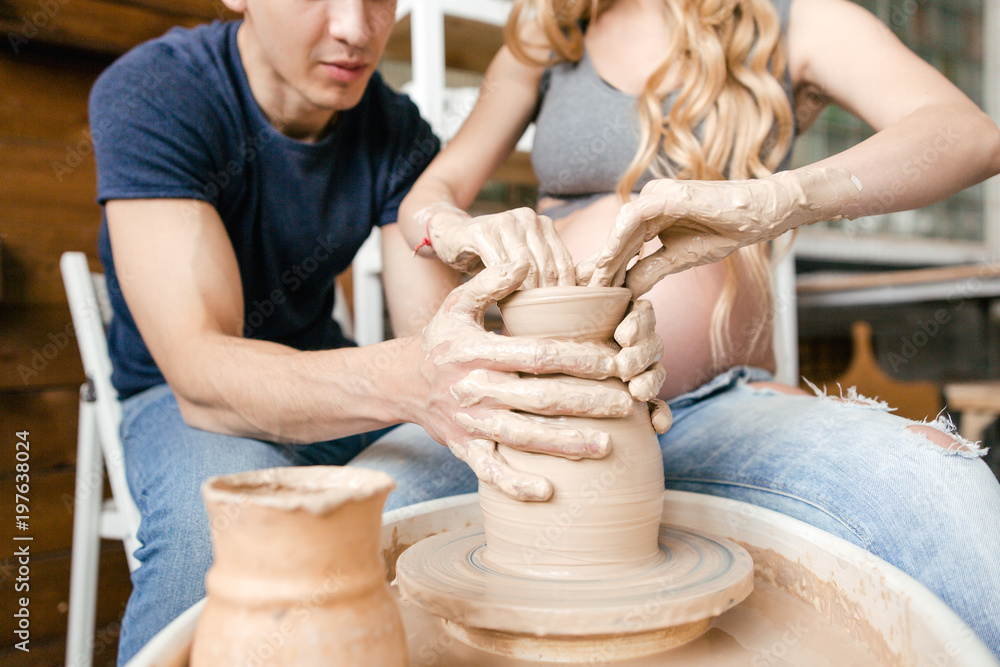 Family young couple make a pot using a pottery wheel in the Studio