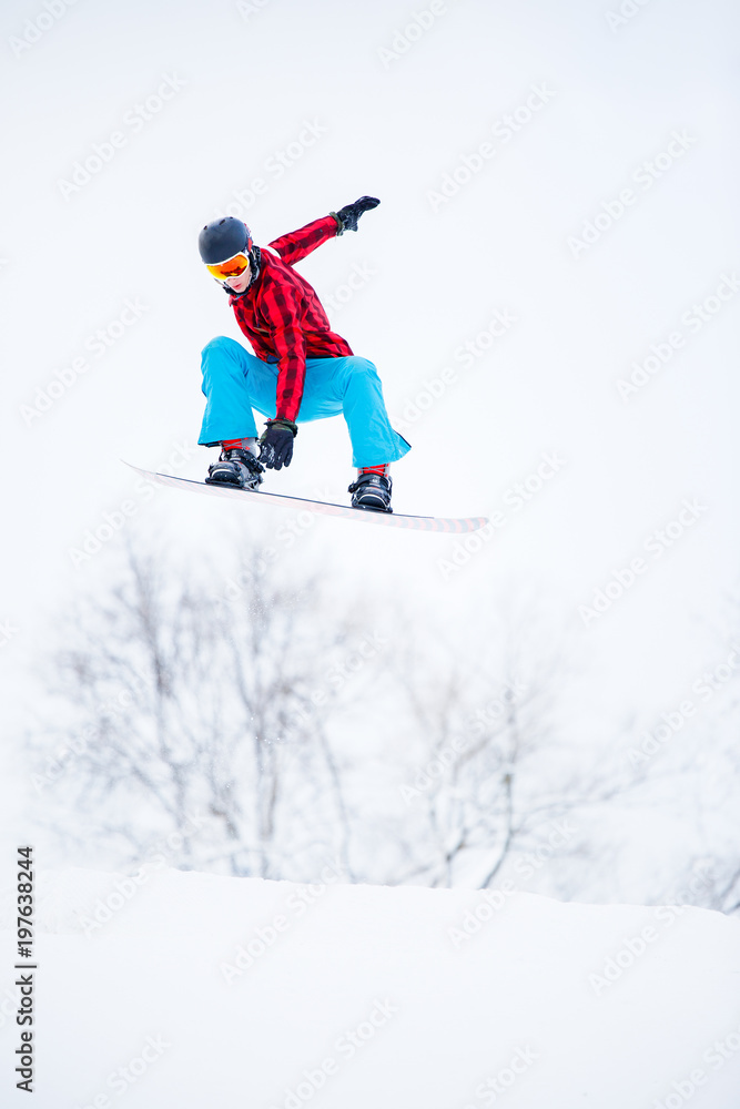 Photo of sportive male snowboarder jumping on snowy hill