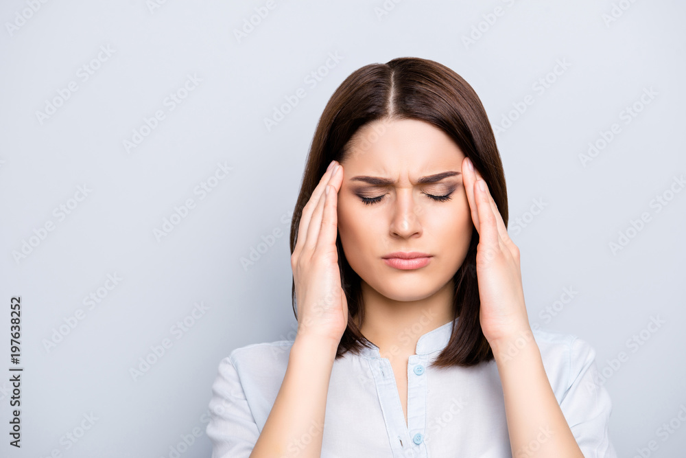 Portrait of upset, sad, pretty, nice, charming, stylish woman in shirt having head ache, stress, troubles, touching temples with fingers and close eyes, standing over grey background Portrait of upset, sad, pretty, nice, charming, stylish woman in shirt having head ache, stress, troubles, touching temples with fingers and close eyes, standing over grey background