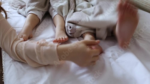 Mom tickled the legs of the children covered with a blanket