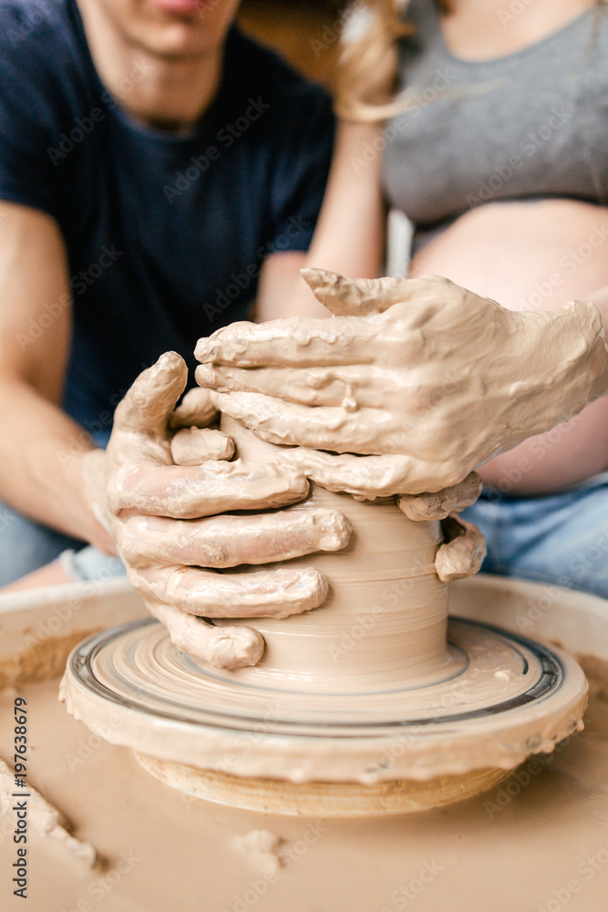 Family young couple make ceramic pot using pottery wheel close up