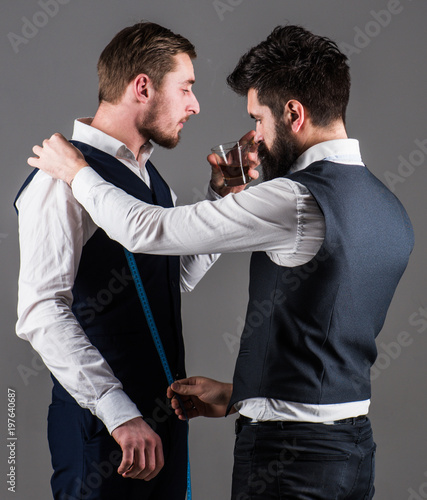 Tailor taking measurements for sewing, grey background.