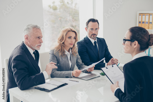 Foto Portrait of young attractive woman in glasses having job interview with three st