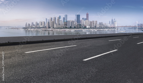 The empty asphalt road is along the modern commercial building in the Chinese city