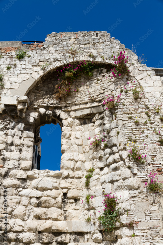 Blumen bewachsenes altes Stein Fenster und strahlend blauen Himmel in Split