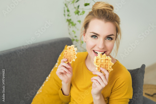Portrait of young pretty woman eating a cookie at home