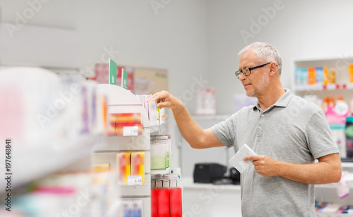 medicine, pharmaceutics, healthcare and people concept - senior male customer with drug at pharmacy