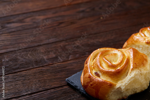 Homemade rose buns on stony cutting board over rustic vintage background, close-up, shallow depth of field photo