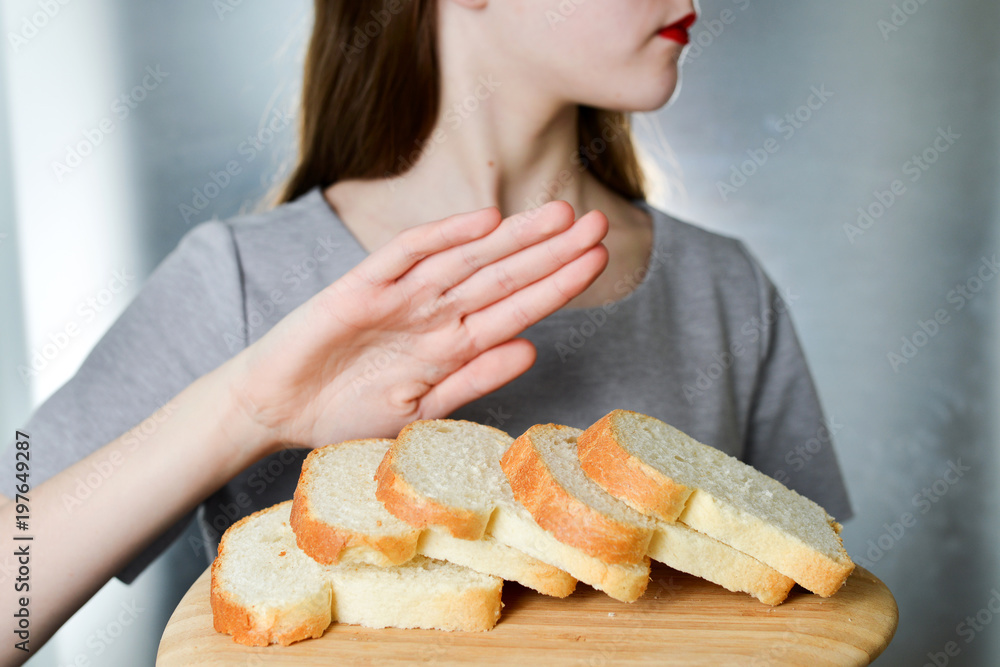 Gluten intolerance concept. Young girl refuses to eat white bread - shallow depth of field Gluten intolerance concept. Young girl refuses to eat white bread - shallow depth of field