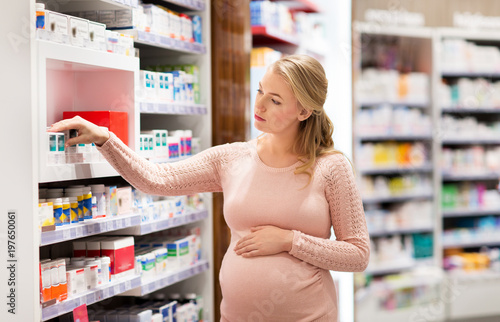 pregnancy  medicine  people  healthcare and expectation concept - happy pregnant woman looking for medication at pharmacy