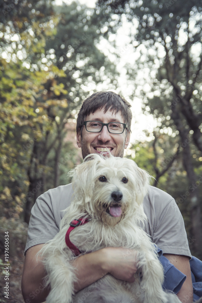 Young man and his lovely puppy in nature - Autumn season - Friendship - Pet owner playing and having fun with his cute dog Young man and his lovely puppy in nature - Autumn season - Friendship - Pet owner playing and having fun with his cute dog