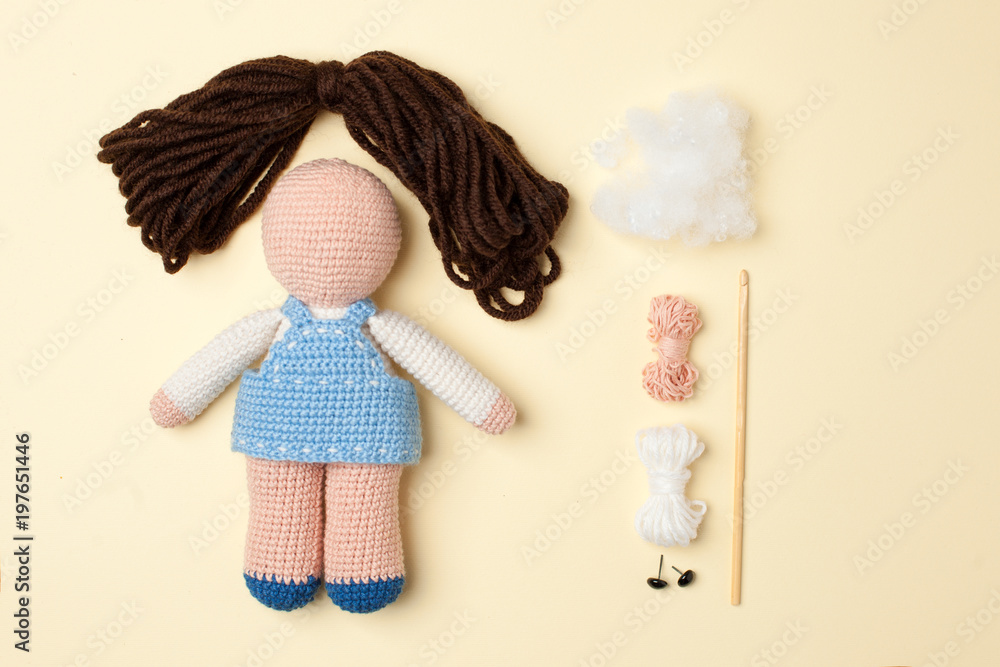 a toy crocheted, a doll in a blue dress, an unfinished work - the hair is not sewn and the decor is not executed, the tools and materials lie nearby a toy crocheted, a doll in a blue dress, an unfinished work - the hair is not sewn and the decor is not executed, the tools and materials lie nearby