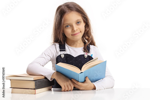 Little girl with a book sitting at a table and looking at the camera