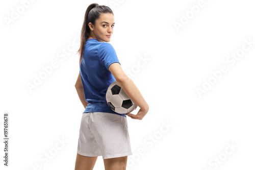 Female soccer player with a football looking over her shoulder