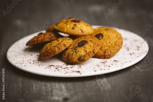 Chocolate cookies placed on a plate on a dark background.