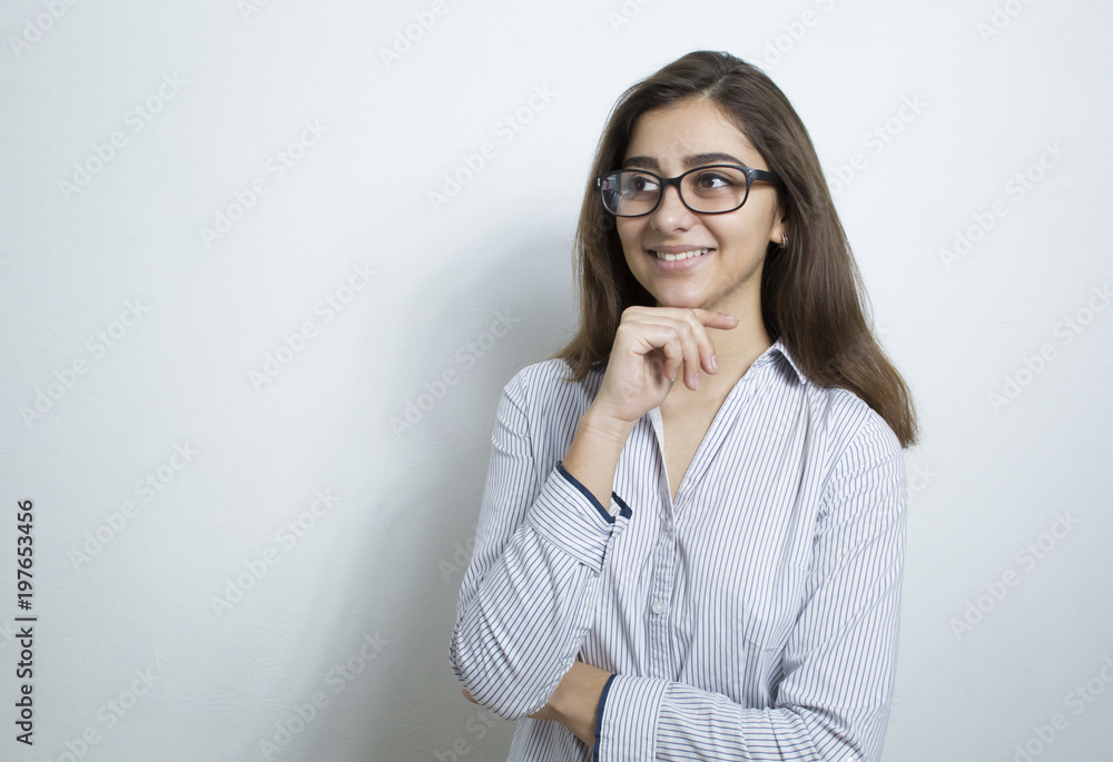 Cute young woman, manager, wearing glasses, thinking about an idea, making a decision. A positive girl in a light business shirt, pondering a thought. White background. Cute young woman, manager, wearing glasses, thinking about an idea, making a decision. A positive girl in a light business shirt, pondering a thought. White background.