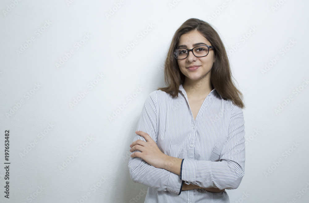 Attractive young woman, brunette, wearing glasses and a business light shirt on a white background. Portrait of a successful Indian girl with arms crossed on her chest. Attractive young woman, brunette, wearing glasses and a business light shirt on a white background. Portrait of a successful Indian girl with arms crossed on her chest.