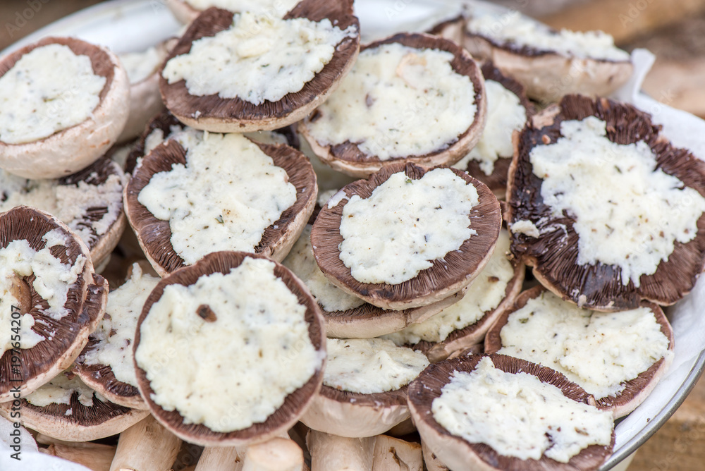 Preparing mushrooms for barbecue on holiday. Mushrooms with cheese spread in bowl. Cooking vegetables. Delicious meal for vegetarians and vegans. Preparing mushrooms for barbecue on holiday. Mushrooms with cheese spread in bowl. Cooking vegetables. Delicious meal for vegetarians and vegans.