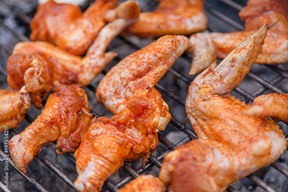 Chicken wings on barbecue grill on hot charcoal and fire. Spicy marinated chicken meat  cooking over the flames