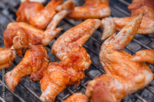 Chicken wings on barbecue grill on hot charcoal and fire. Spicy marinated chicken meat cooking over the flames